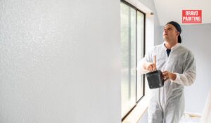 A Man In A White Coverall Holding A Bucket And A Paint Brush