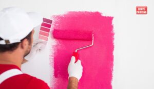 A Person Painting A Wall With Pink Paint