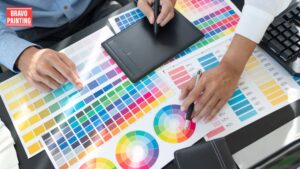 A Person'S Hands Holding A Pen And A Tablet Over A Table With Color Swatches