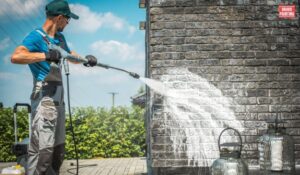 A Man Spraying A Wall With A Hose