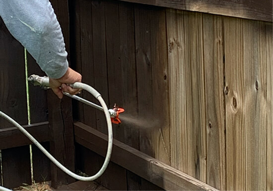 Freshly painted wooden fence in a backyard with clean, even coating under natural sunlight.
