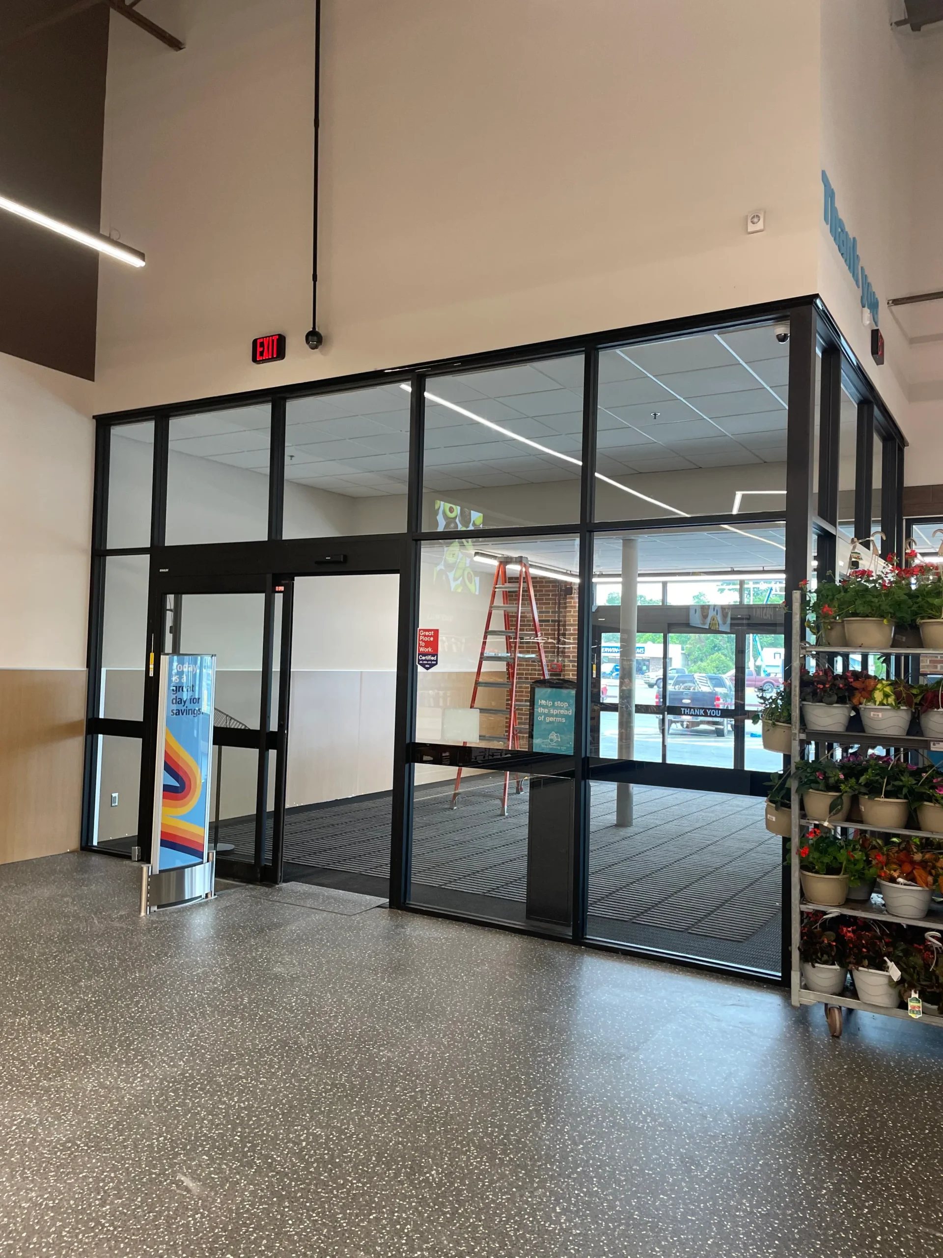 a glass door with a sign and a shelf with plants