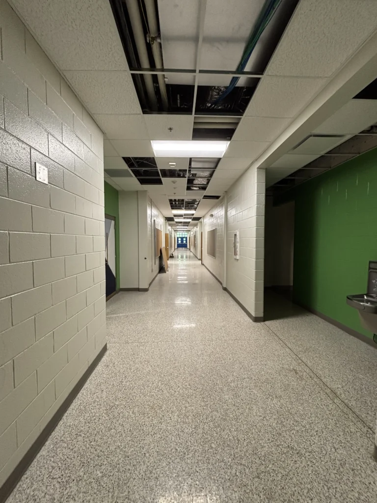 a hallway with a green wall and a sink